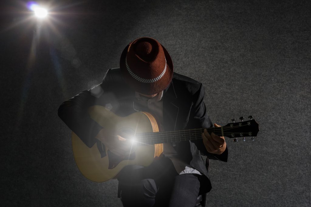 musician playing the guitar on spot light background, musical concept